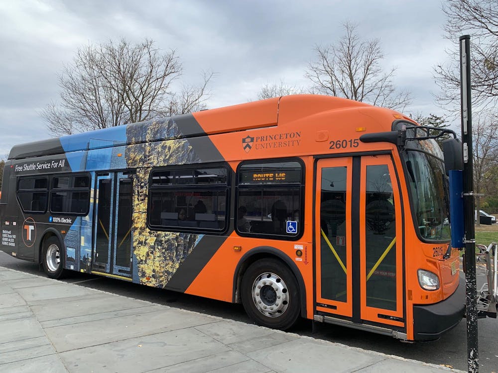 An orange and black bus is parked against a curb.