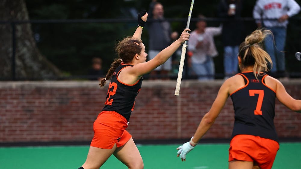 Two Princeton field hockey women athletes celebrating a goal on a field. 