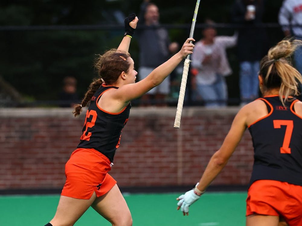 Two Princeton field hockey women athletes celebrating a goal on a field. 