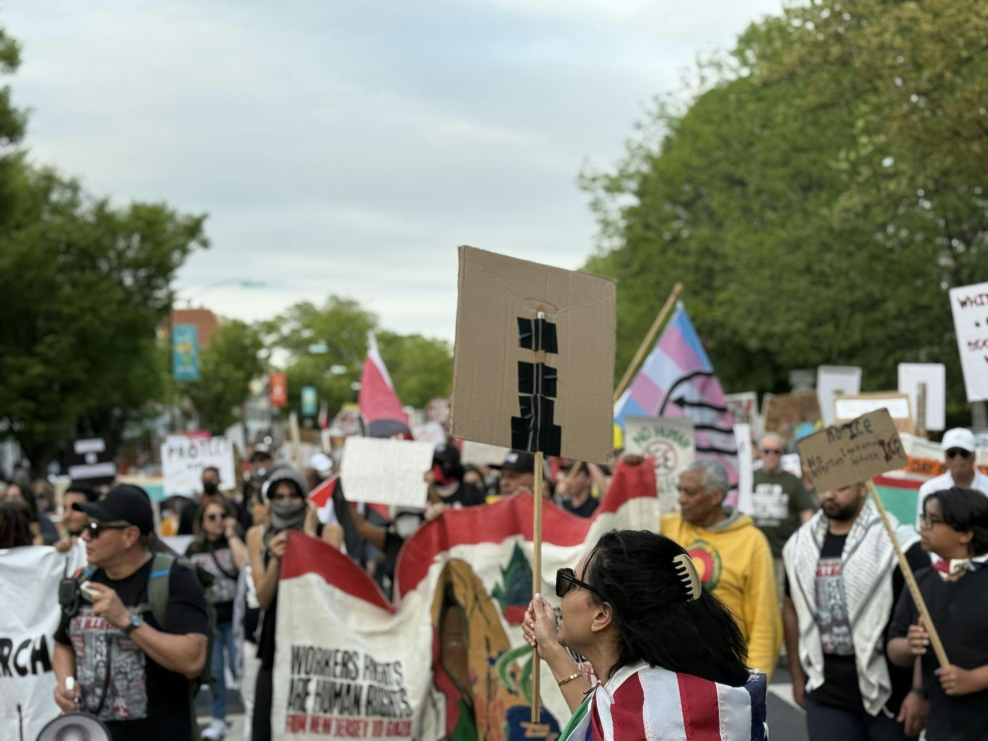 A crowd of people are marching down a street. They are holding signs.