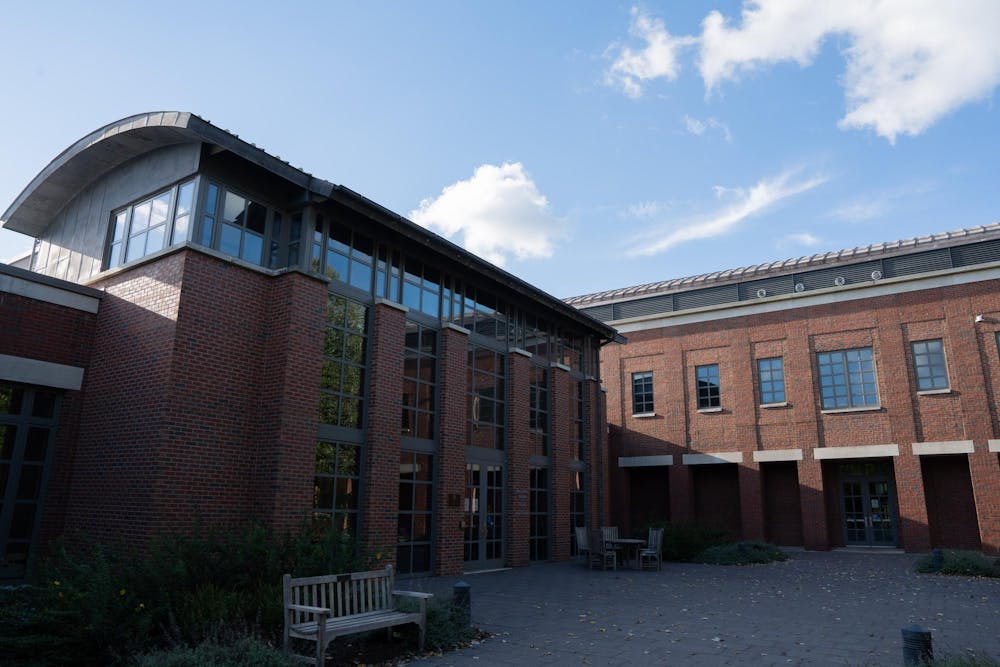 A brick building with large windows, against a blue sky with scattered clouds