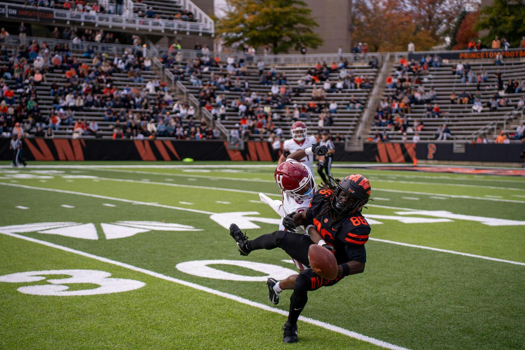 A man crouching in midair is tackled by another man diving directly towards the viewer. 
