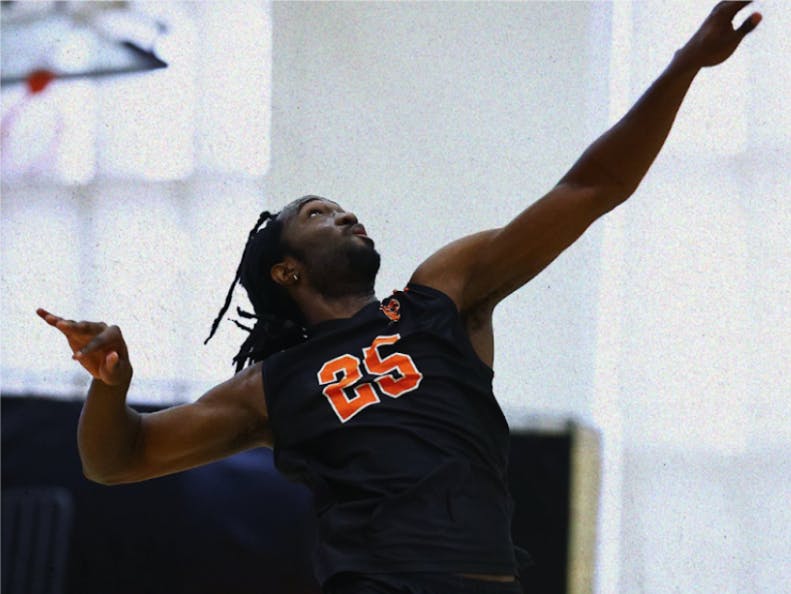 Man wearing black jersey with an orange “25” on it winding up for a hit.