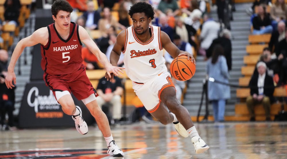 A player in a white jersey is dribbling a basketball and being guarded by a player in a red jersey
