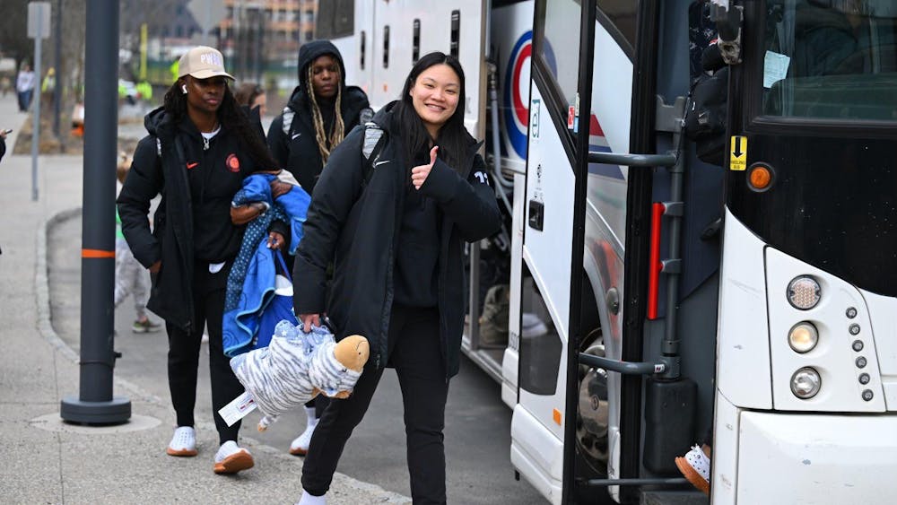 Three girls wearing black Princeton Athletics coat boarding a Coach bus on a residential street. 