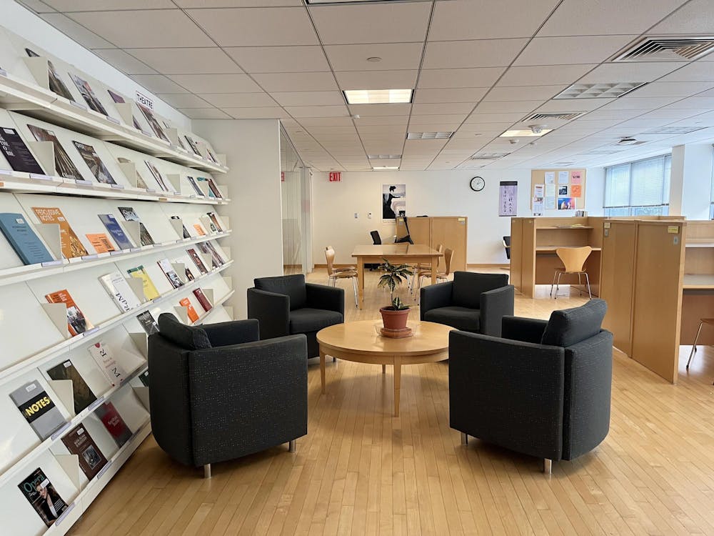 Study space with wooden floors and four cushioned black chairs.