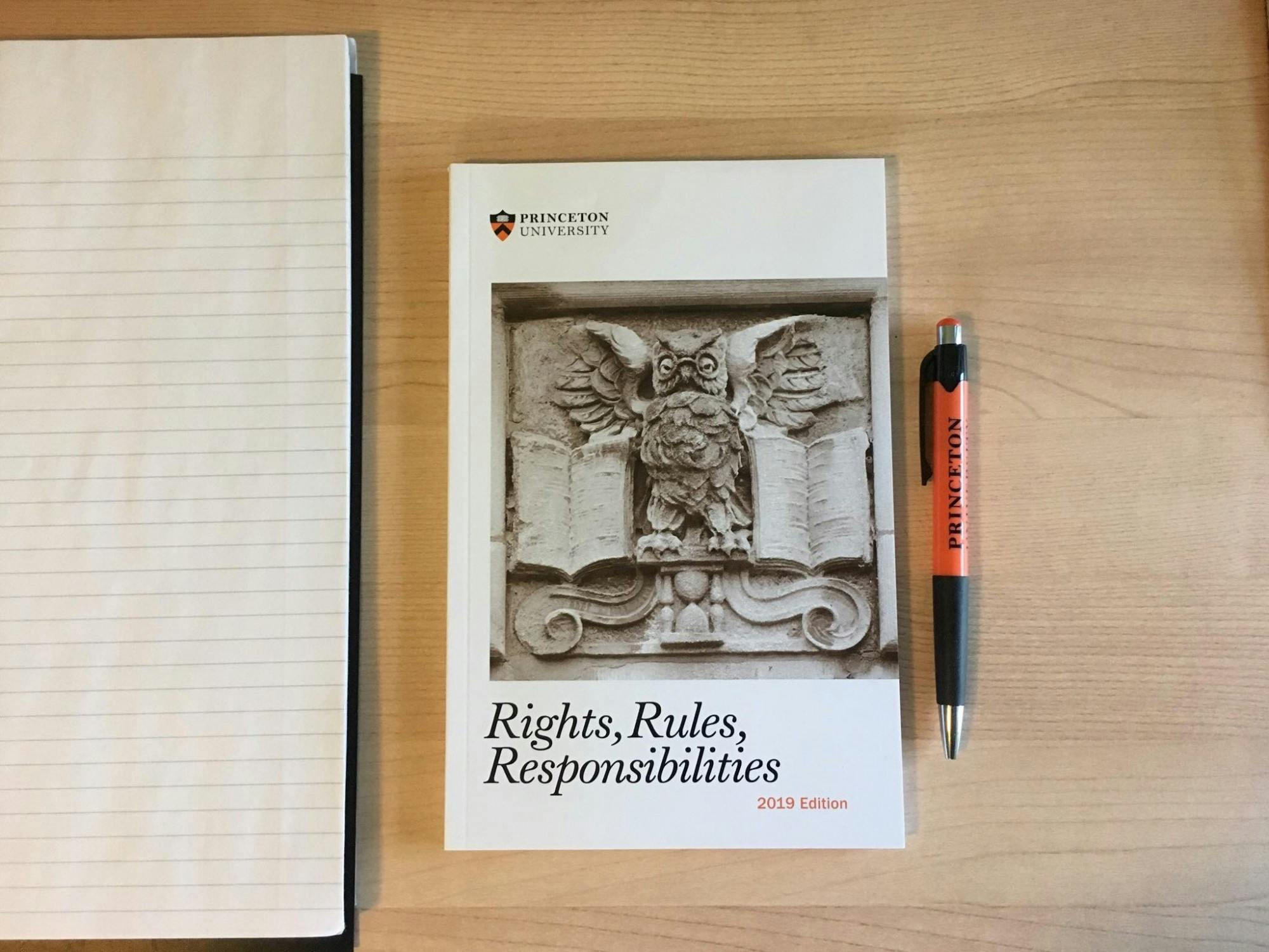 A book titled “Rights, Rules, Responsibilities” with a pen to the side on a wooden desk.
