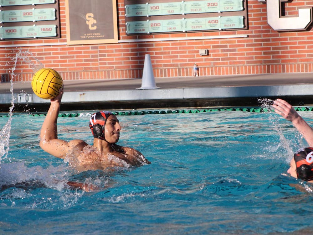 A man in the water with a water polo ball in his hand ready to shoot towards the goal