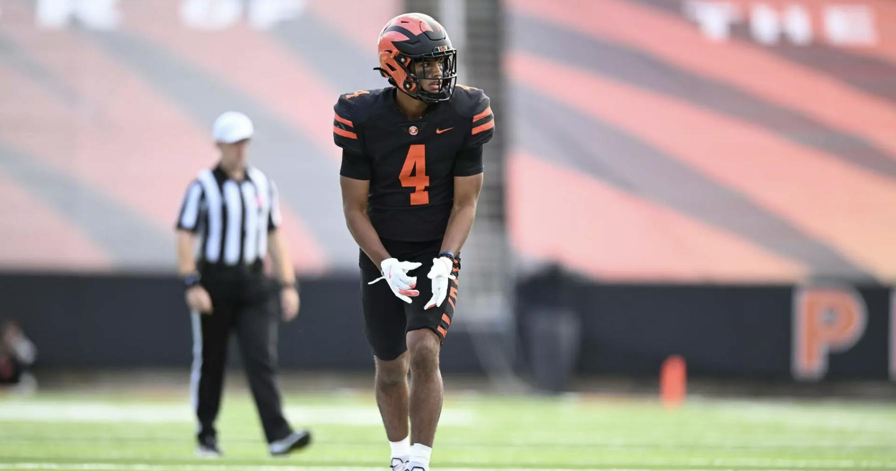 A player in a black and orange jersey lines up to run a route.