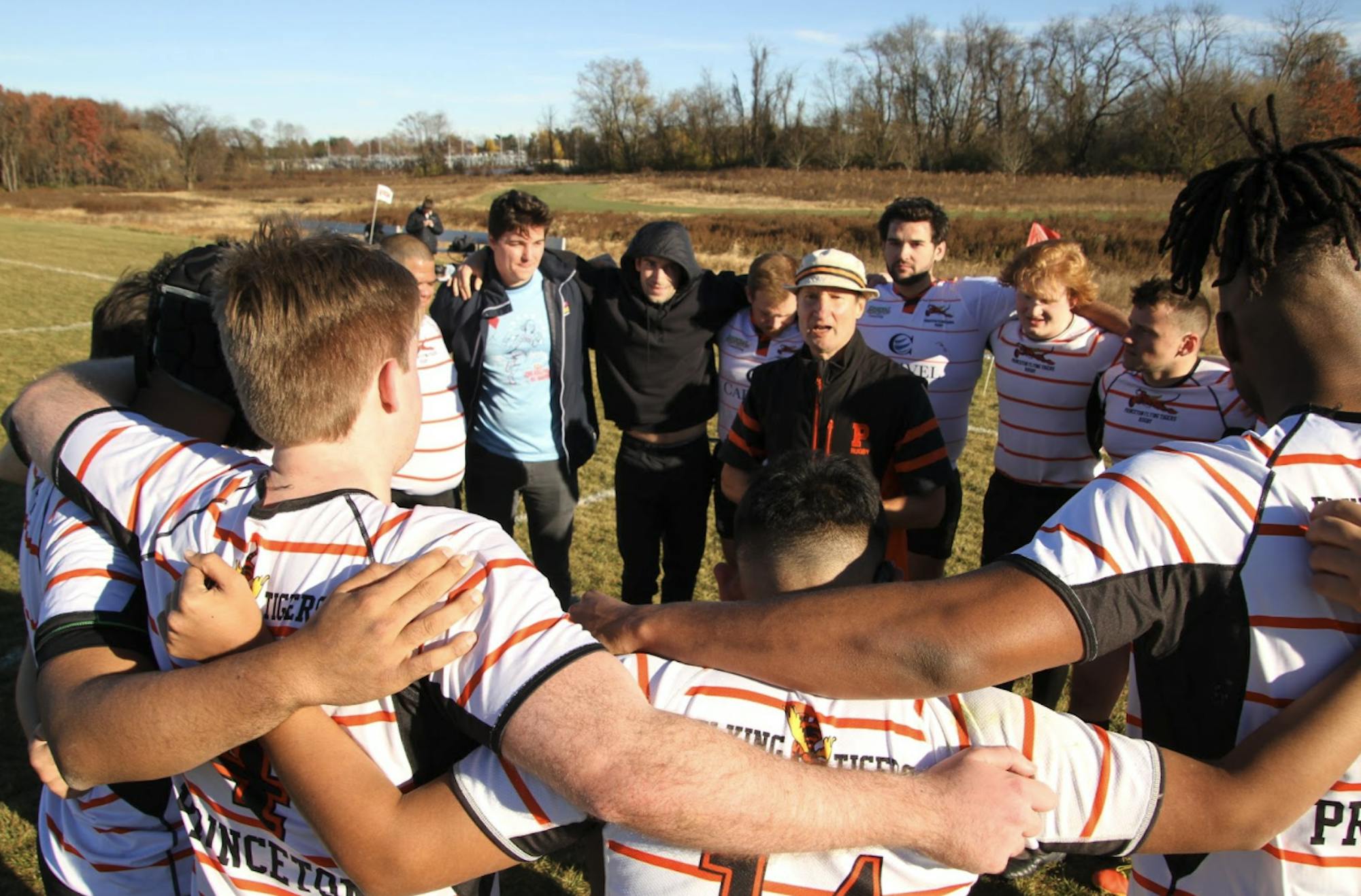 Alumni and current men’s rugby players huddle around Richard Lopacki, head coach of Princeton men’s rugby team from 2000 to 2023.