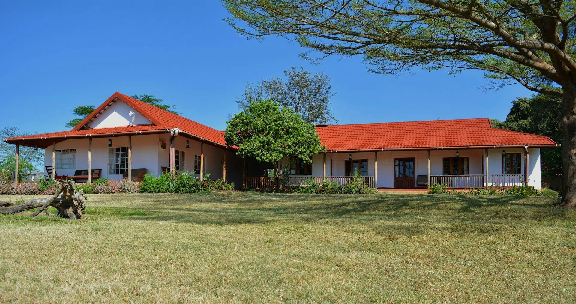 A long ranch house with a red roof and with white walls. 
