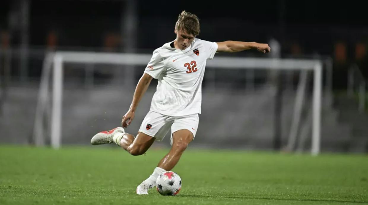 A player in a white jersey is about to hit the soccer ball. 