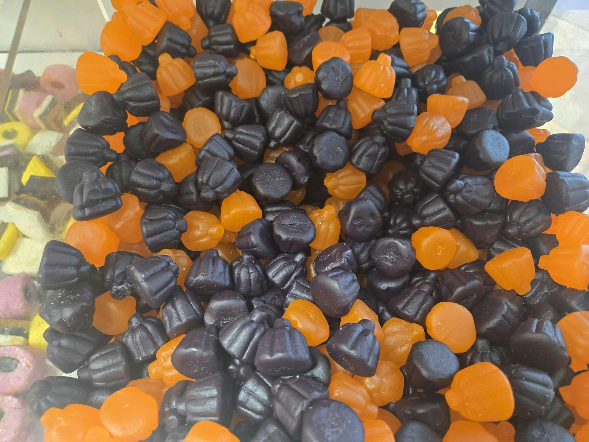 Black and orange gummy candy pumpkins are in a clear plastic box.