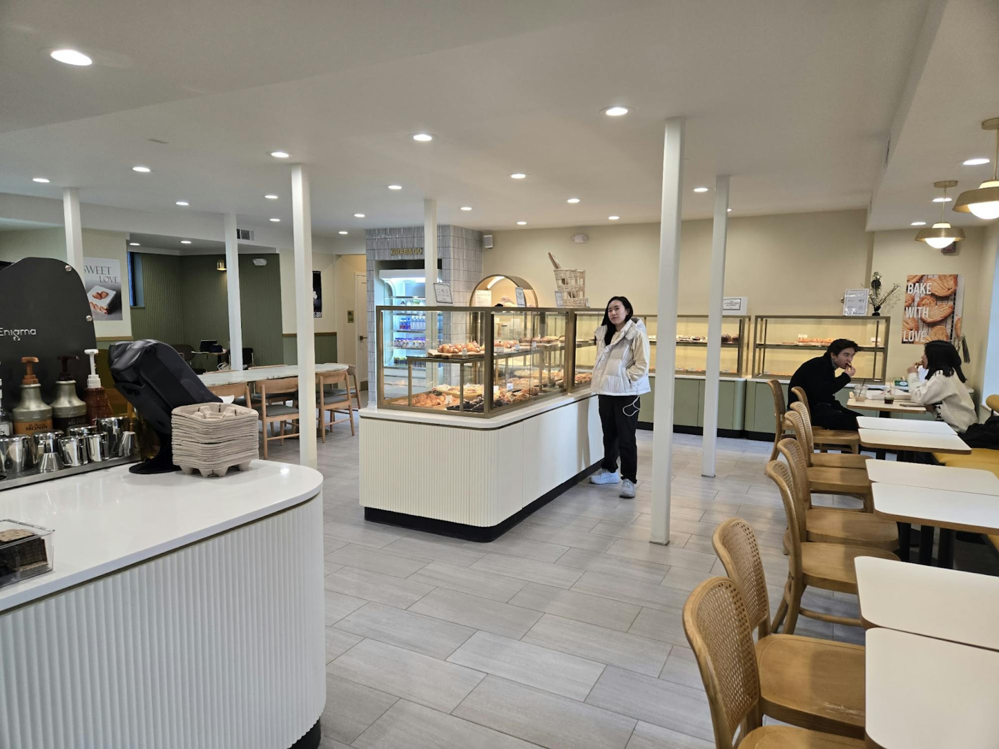 Display cases containing the pastries available for purchase, with seating areas all around the interior and the service counter on the left side.