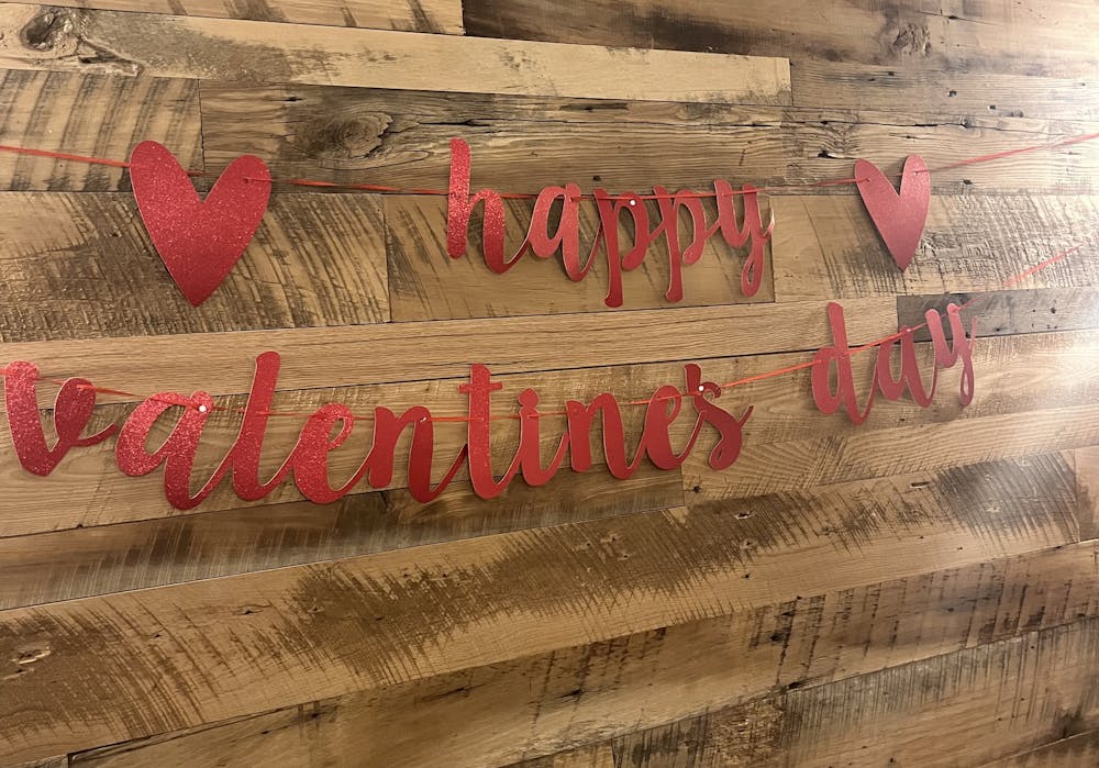 Red letters spelling out “Happy Valentine’s Day” sits against a wood-paneled wall.