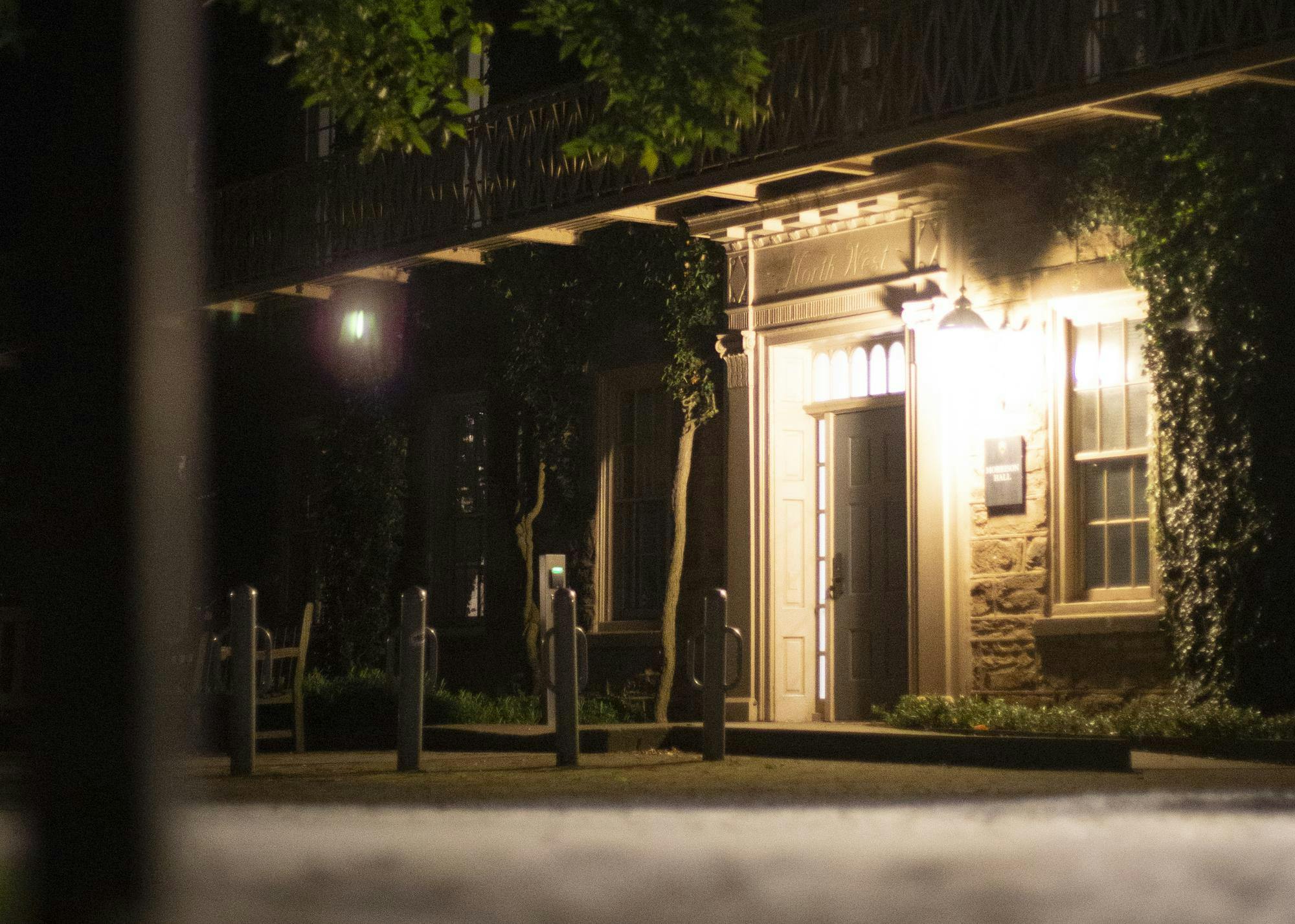 Front of Morrison Hall at night, lit up by the lights by the door. 