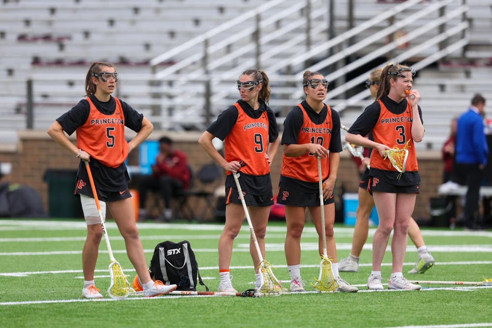 Four women’s lacrosse players looking around on a training pitch.