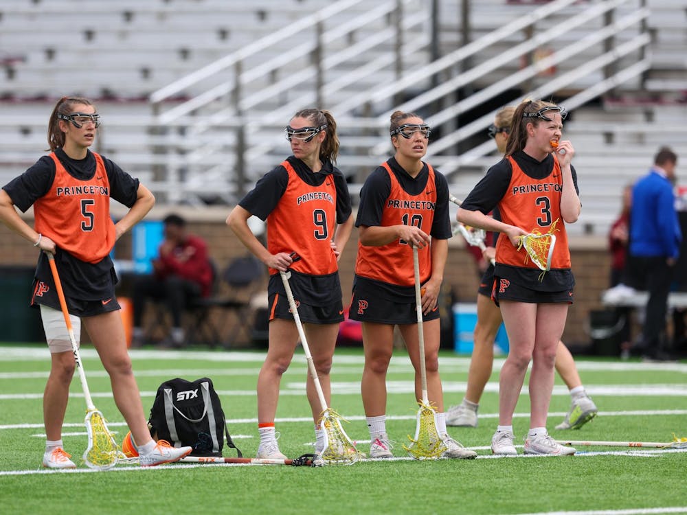 Four women’s lacrosse players looking around on a training pitch.