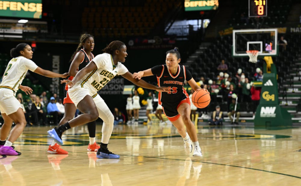 A player in a black jersey dribbling a basketball, being guarded by a player in a white jersey.