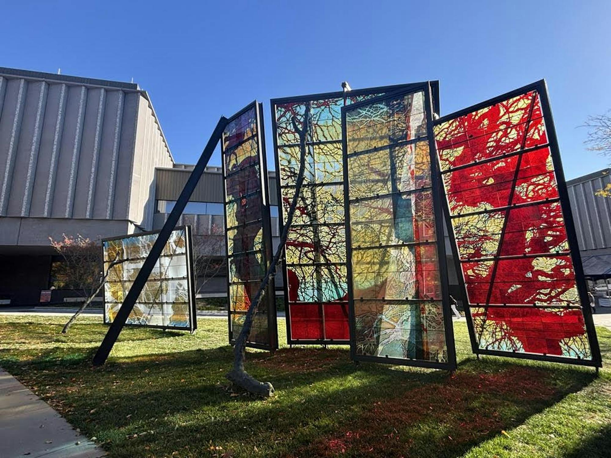 Five colorful glass planes with vivid colors of red and green sit propped vertically outside.