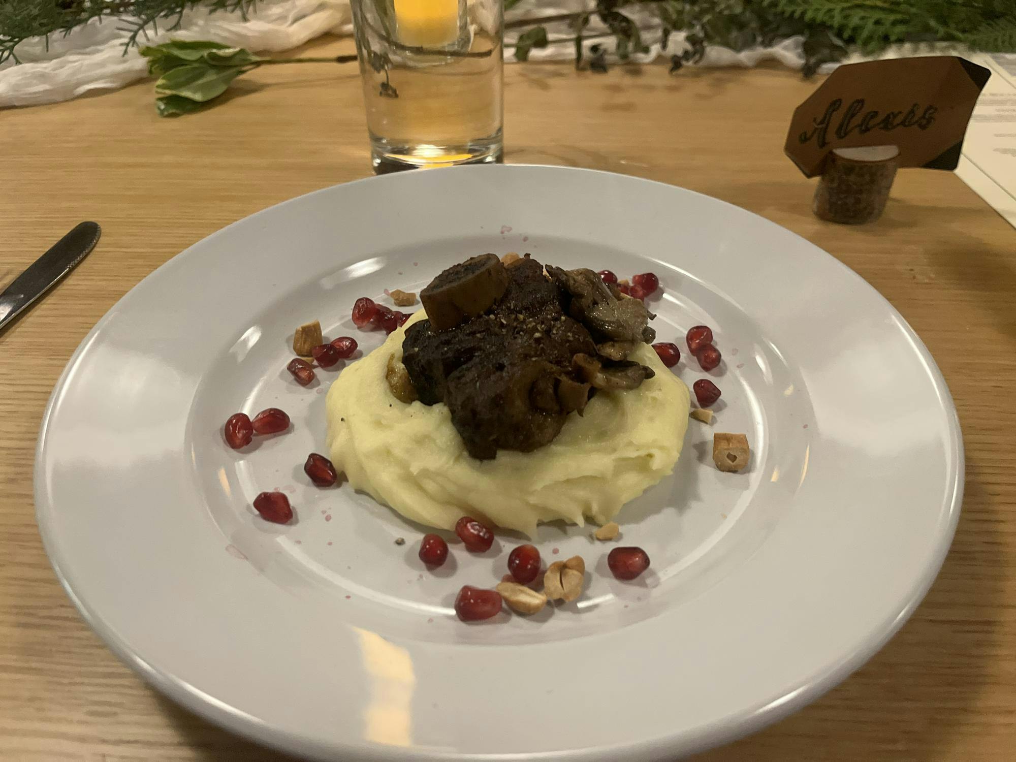 A brown piece of meat is on a pillow of pale yellow potatoes.