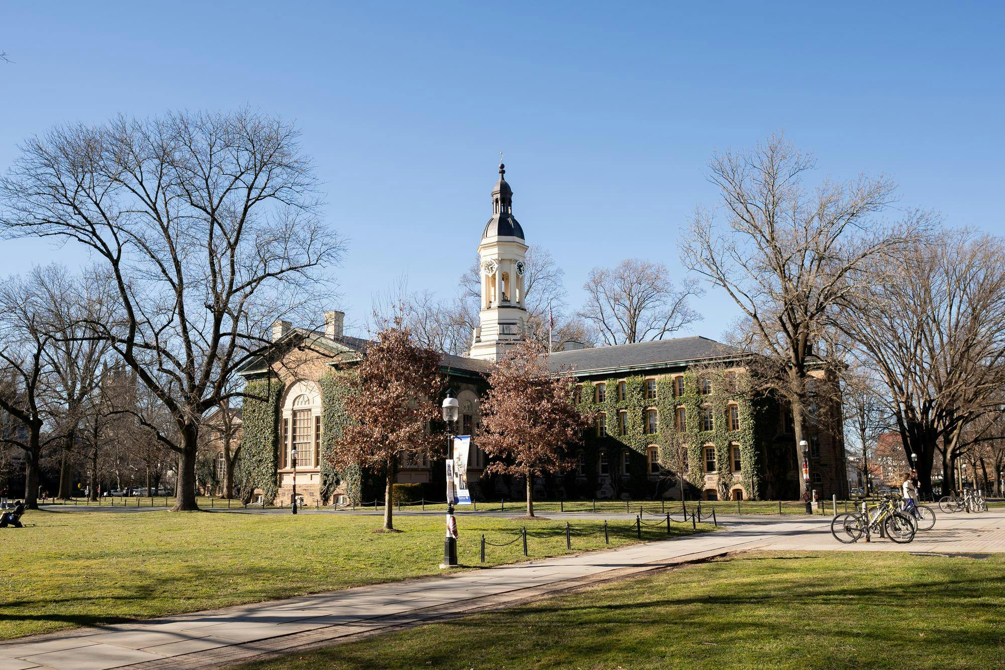 Green lawns in front of an old, ivy-covered building with blue skies in the background.