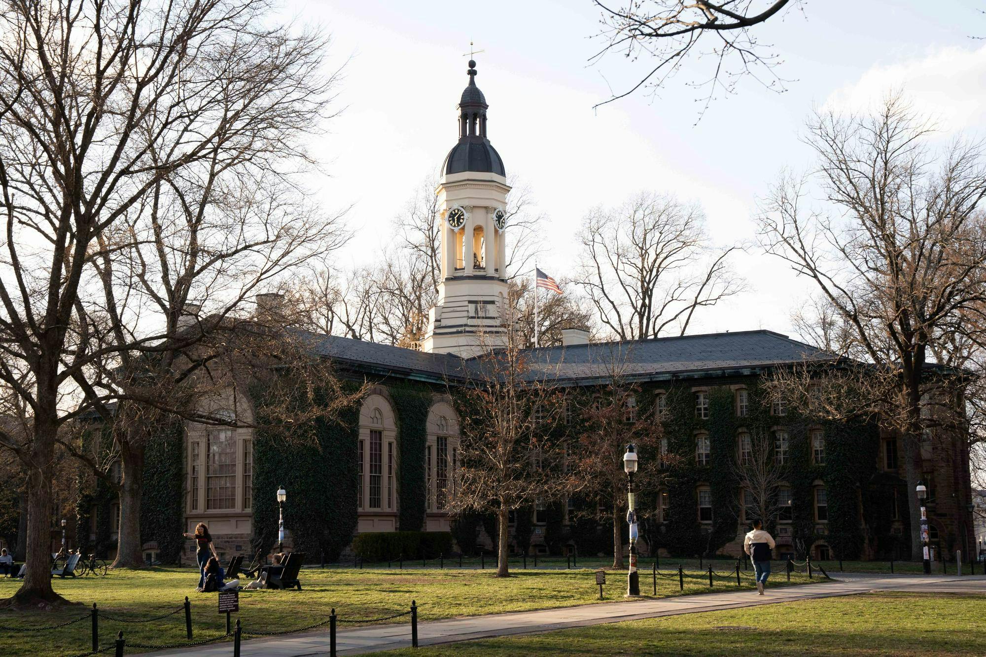 A large building covered in ivy. There is a clock tower in the center.