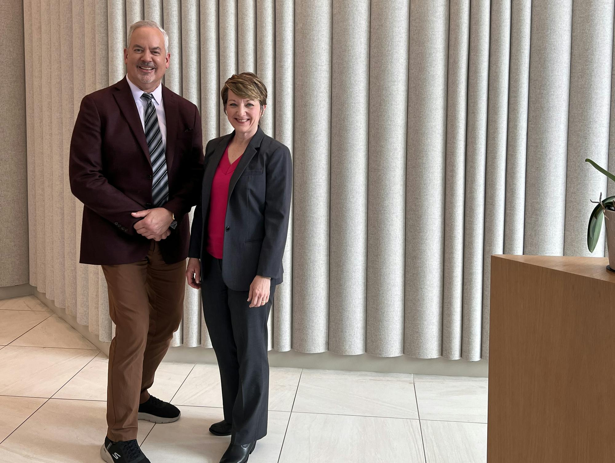 Man and woman in front of beige curtain.