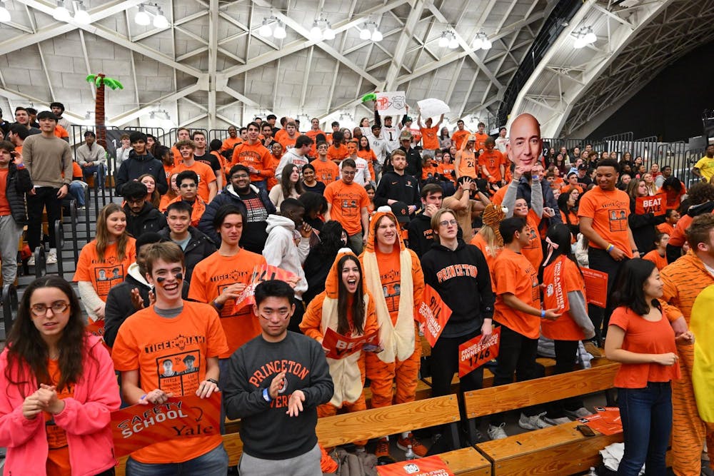 People dressed in orange and holding signs stand on crowded bleachers.