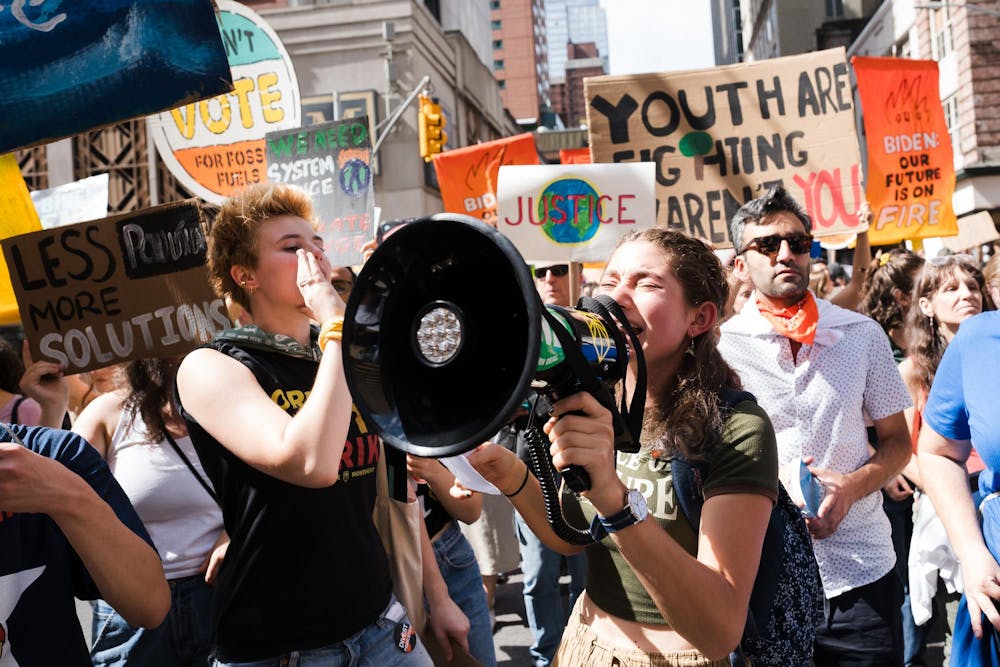 Students are holding megaphones and posters at a climate protest. 