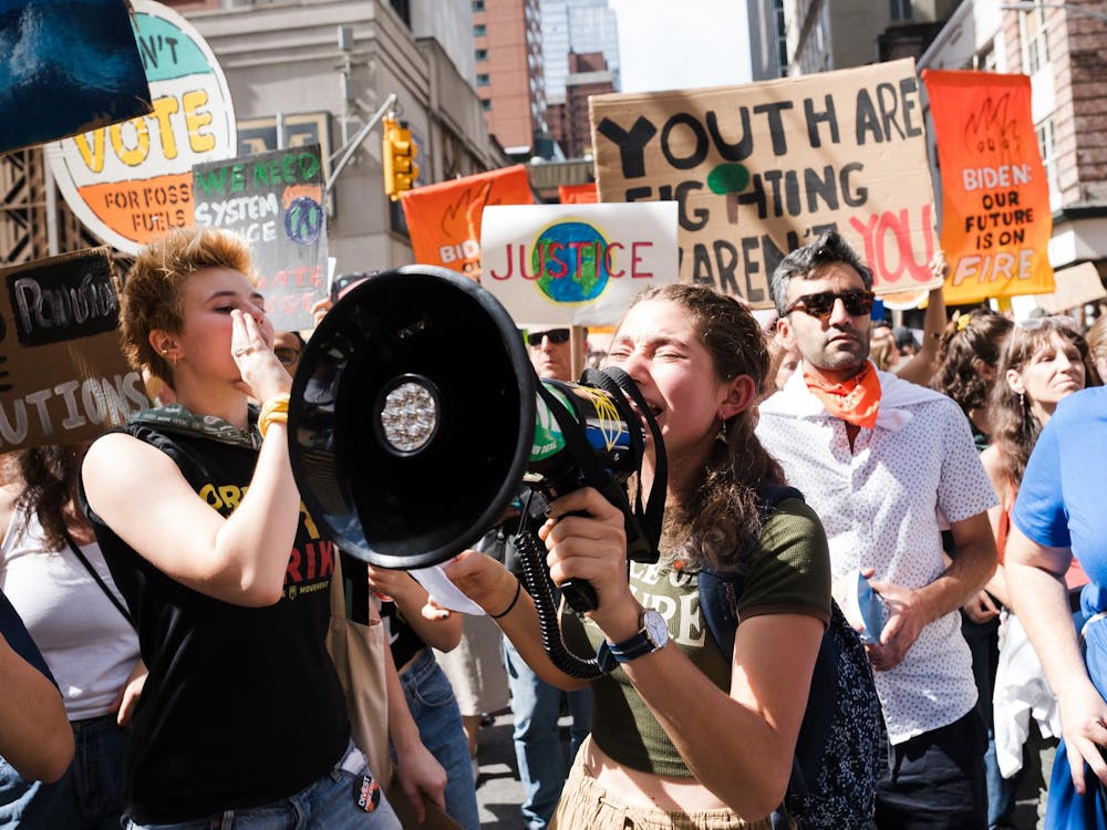 Students are holding megaphones and posters at a climate protest.