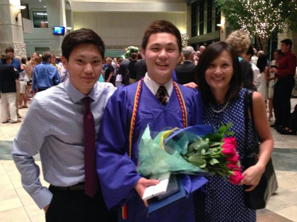  Tobias Kim '17 poses with his brother and with his mother, Joanna, after high school graduation.
