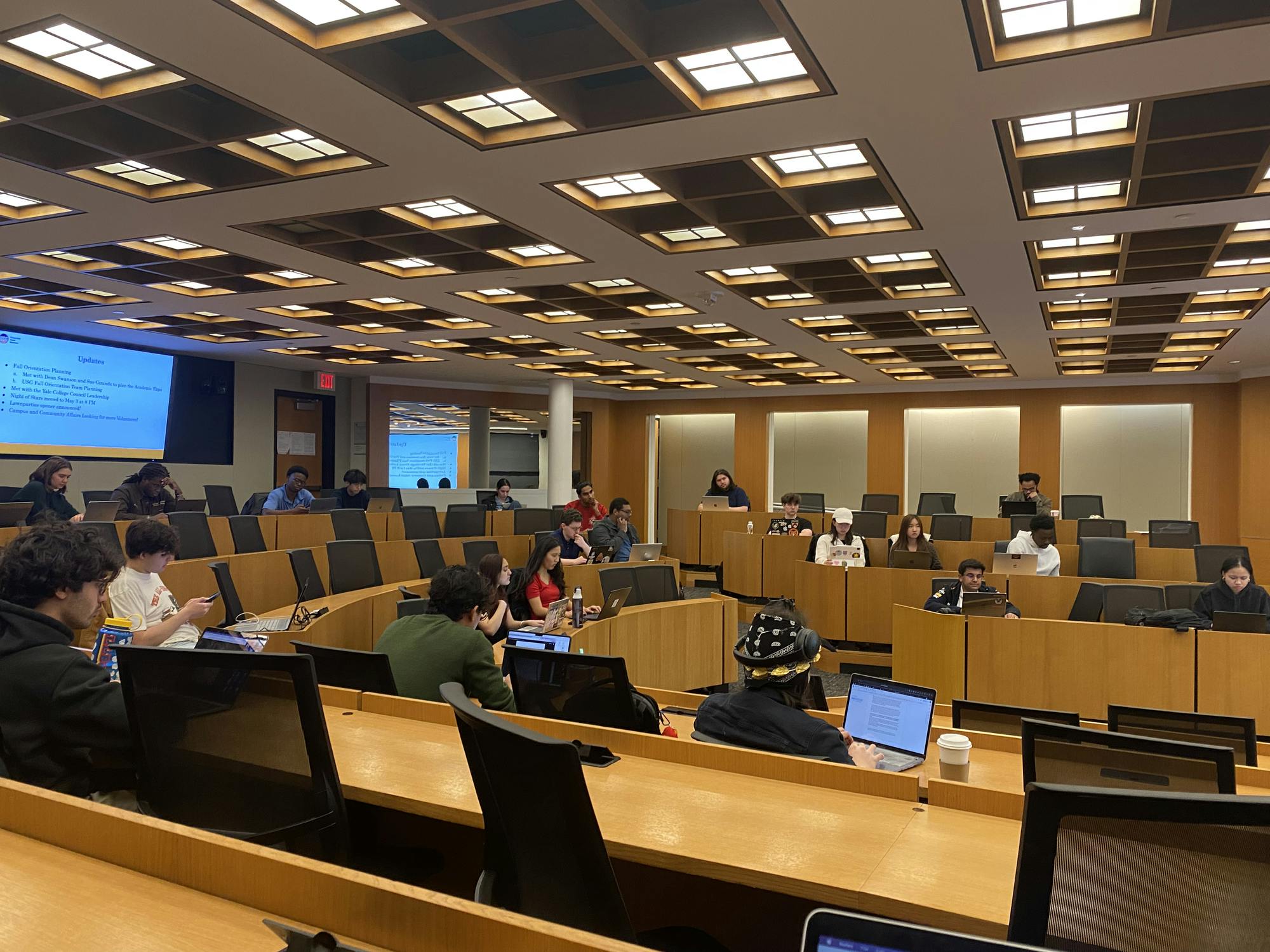 A number of people sitting in a horseshoe.