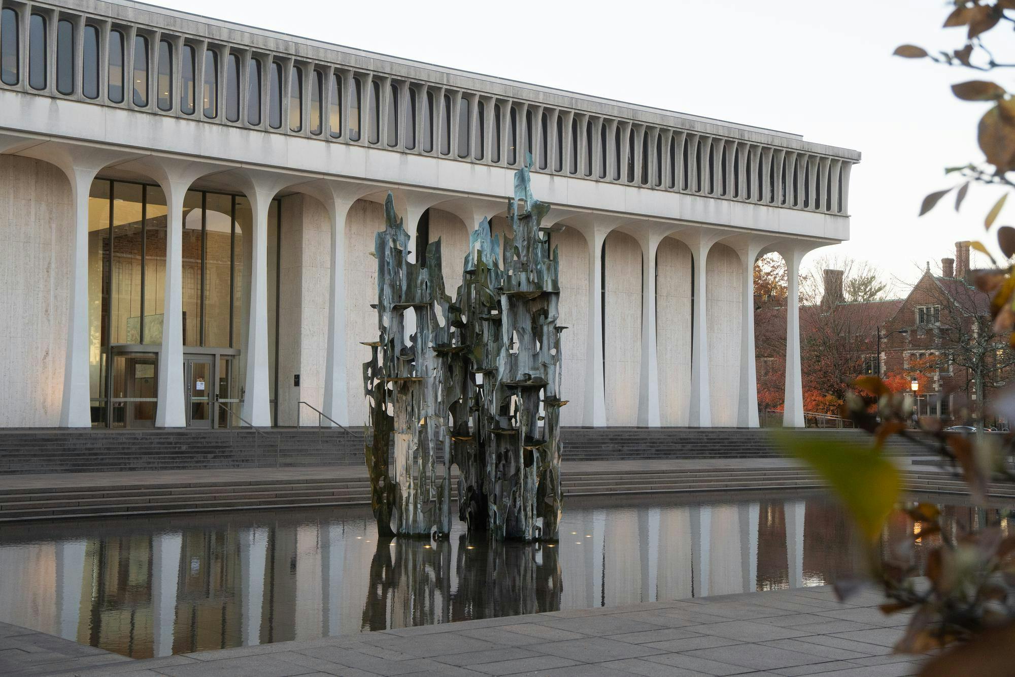 A green rusted fountain in front of a white-columned building.
