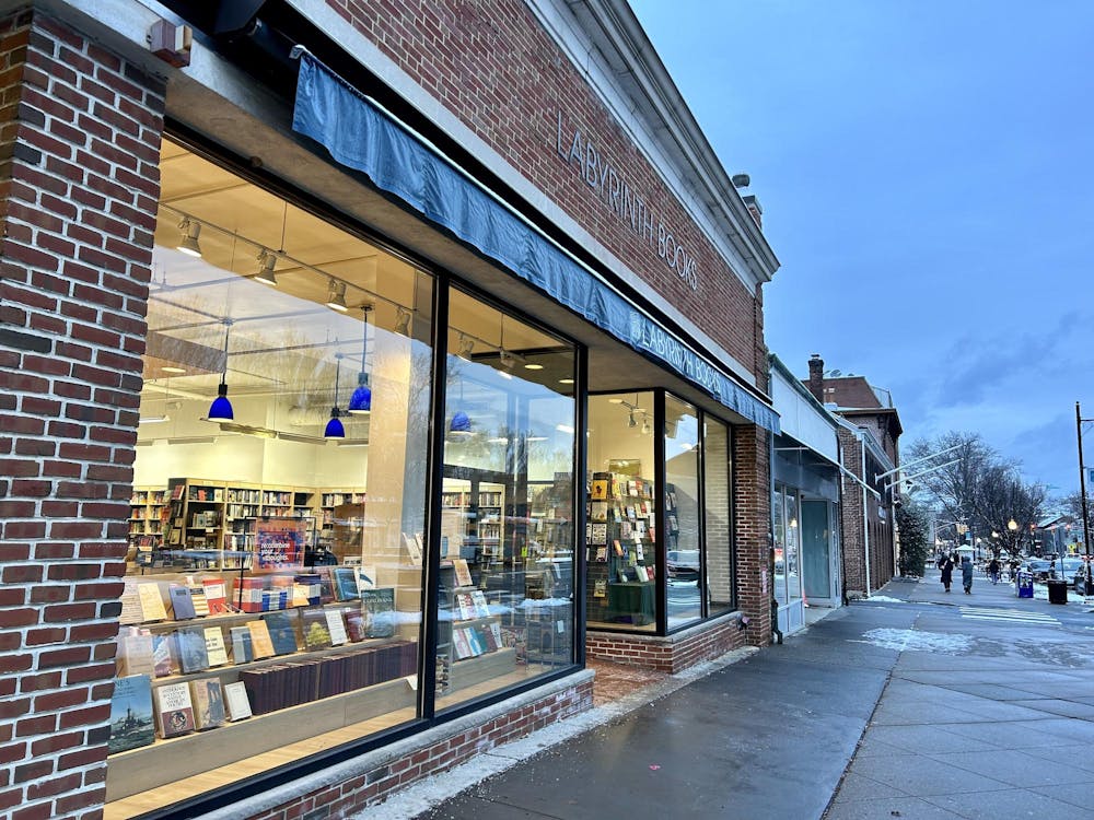 A brick building sits alongside a icy sidewalk. The building has windows in front and there are books in the windows. The sign above the windows reads "LABYRINTH BOOKS" just above a blue awning.