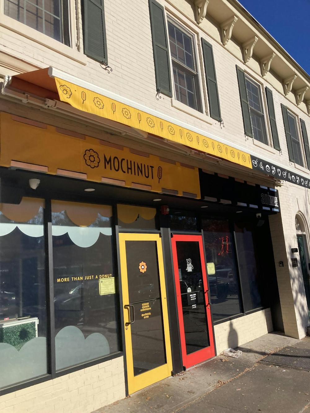 A yellow restaurant storefront with the words "Mochinut" and a black storefront next to it with the words "Ani Ramen."  