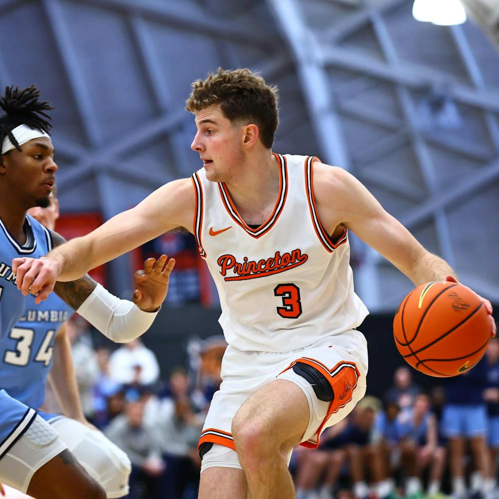 A player in a white and orange jersey dribbles a basketball.