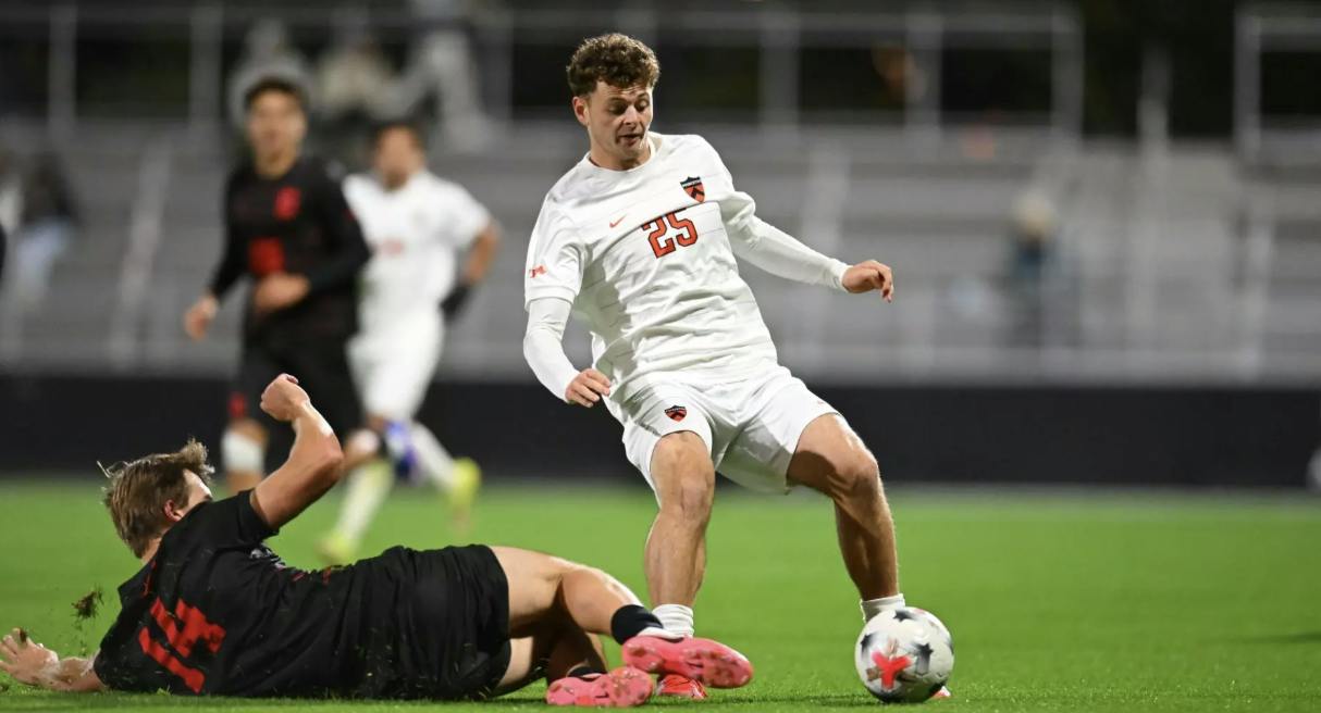 Princeton soccer player dribbling around a Cornell defender.