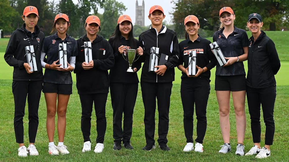 A group of people pose with a gift in their hand and a trophy. 