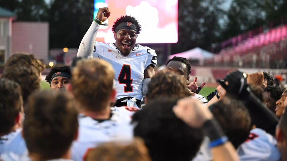Football player sitting atop teammates celebrating.