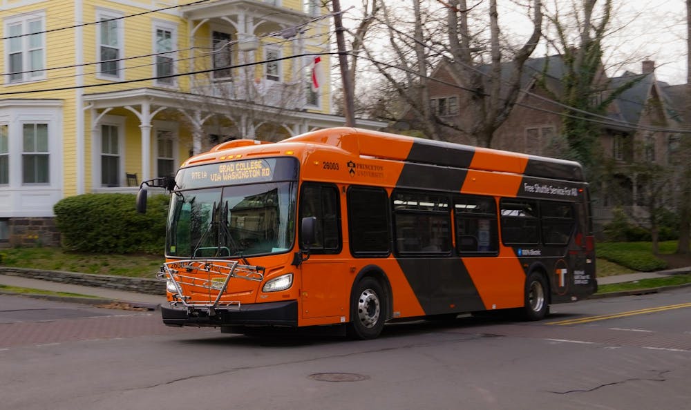 An electric orange-and-black bus with the Princeton University logo and the words “Free Shuttle Service For All” written on the side.