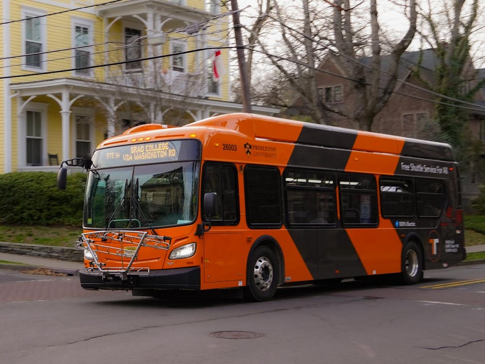 An electric orange-and-black bus with the Princeton University logo and the words “Free Shuttle Service For All” written on the side.