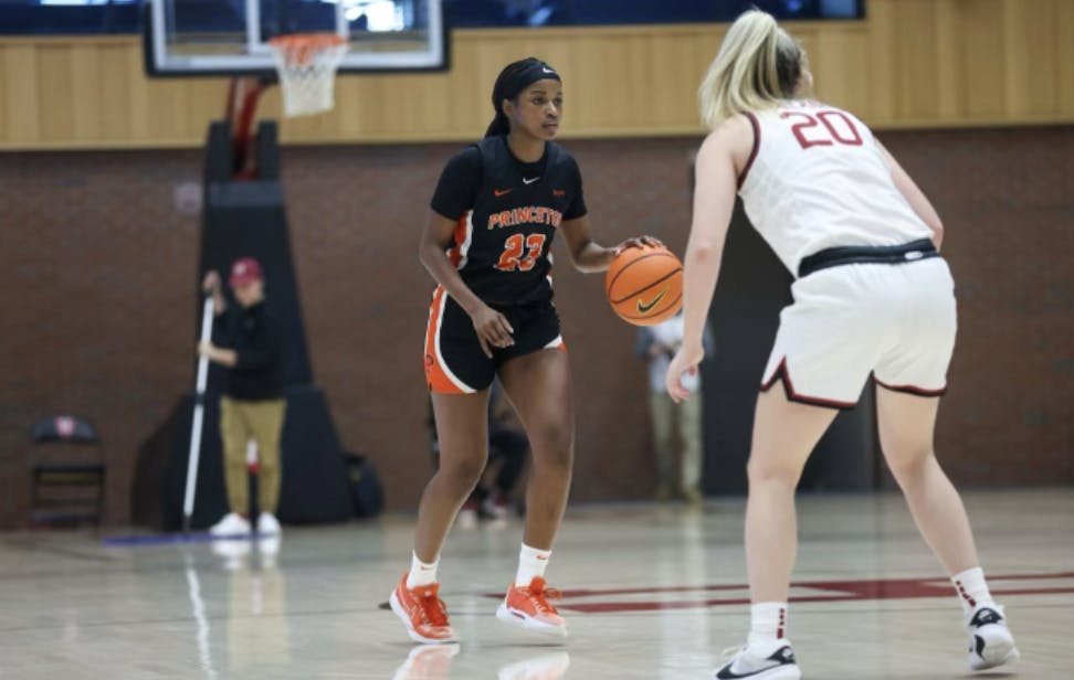 Woman in black jersey dribbles down basketball court.