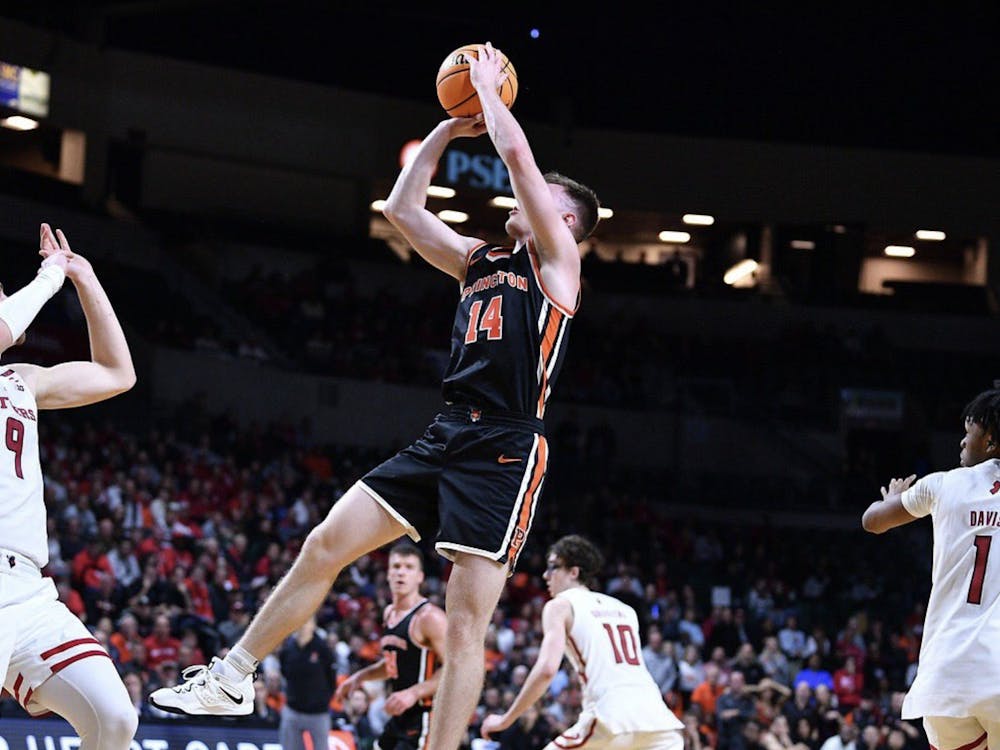 A male Princeton basketball player (14) with a ball in his hands ready to shoot surrounded by three men in white jerseys.
