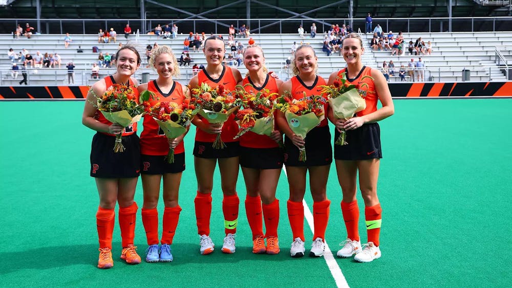 Six women stand for photo in field hockey uniforms.