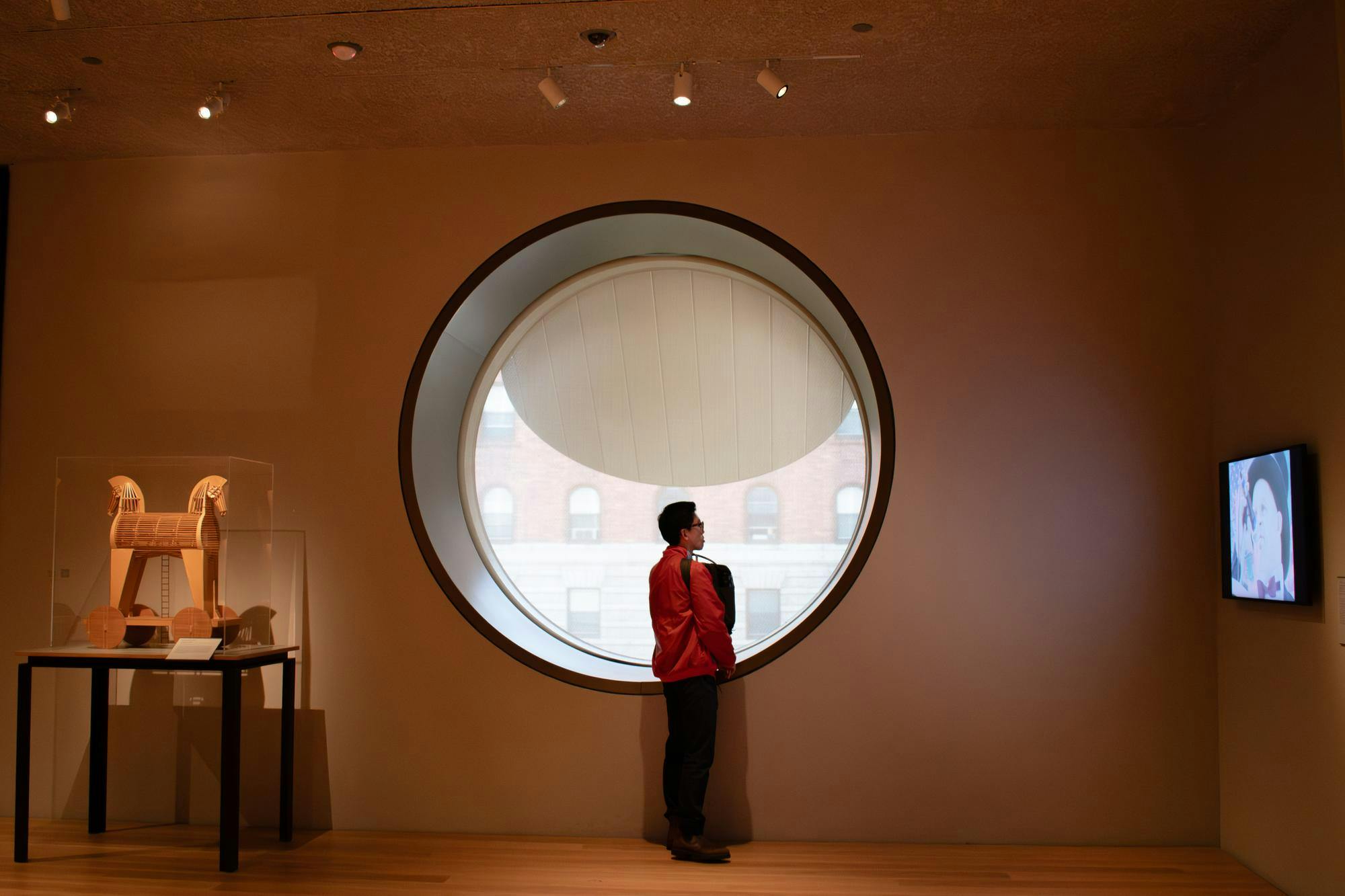 A woman stands next to a window in an art museum.