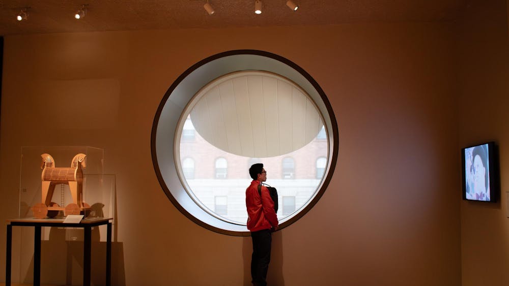 A woman stands next to a window in an art museum.