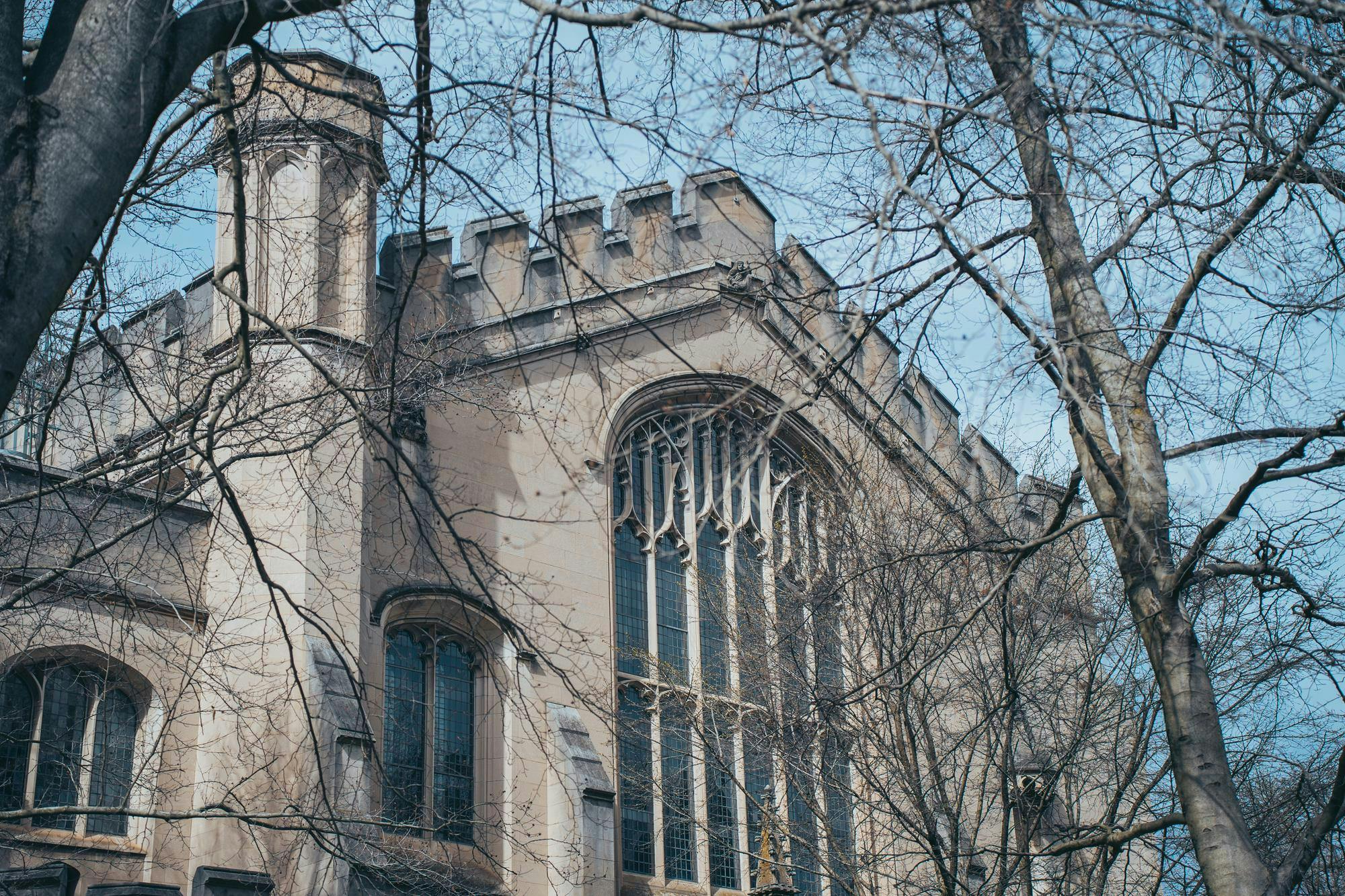 A gothic stone building with barren trees in front.