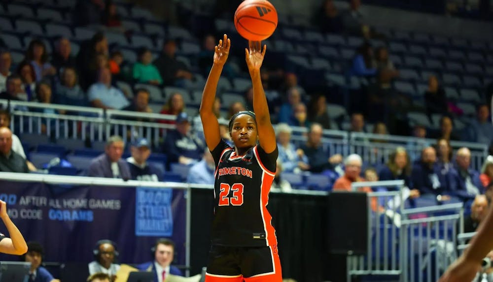 A woman in a black Princeton jersey shoots an orange basketball.