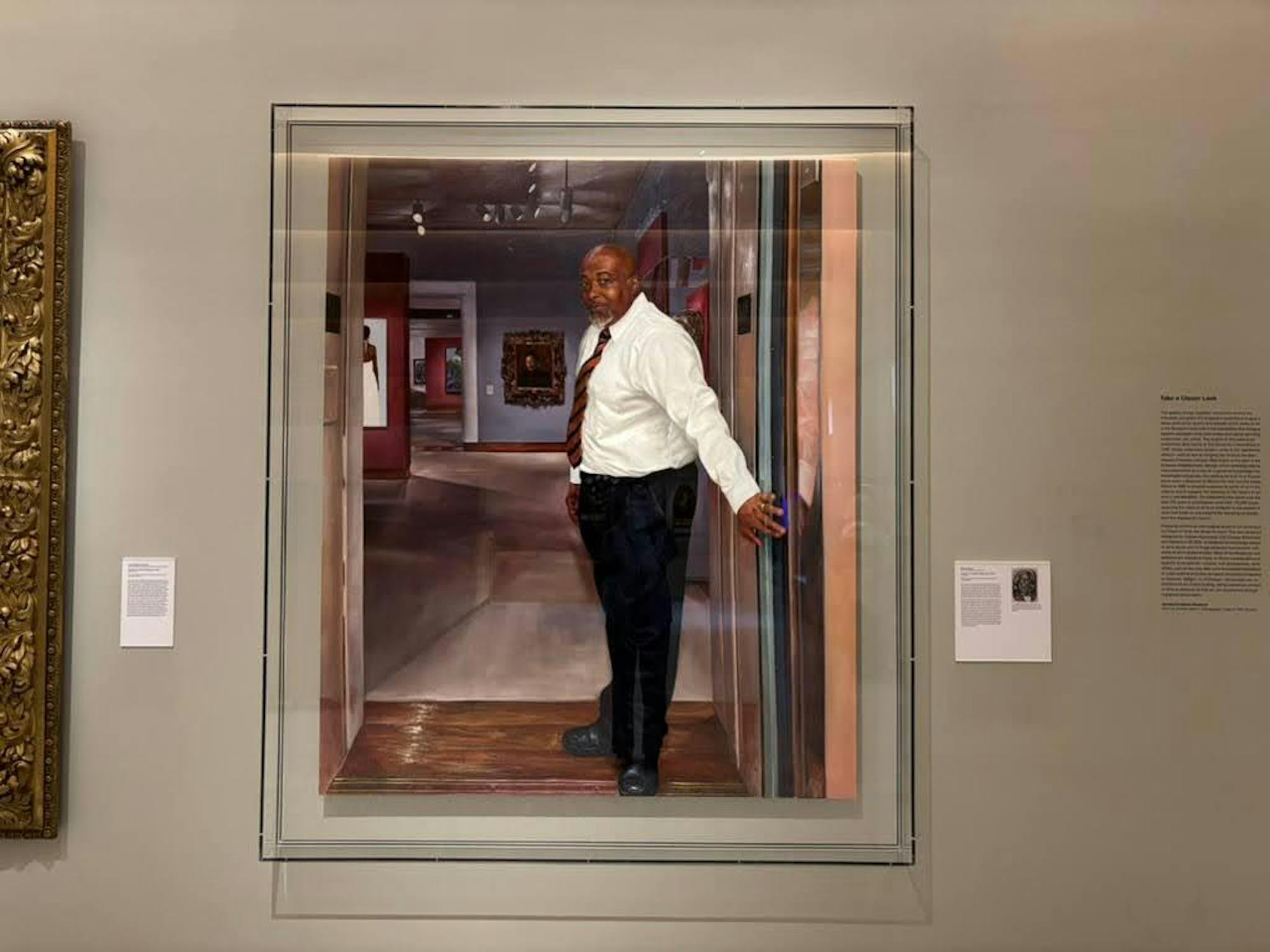 A glass-encased painting of a museum security guard holding an elevator door to a gallery.